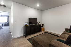Carpeted living area with baseboards and a textured ceiling