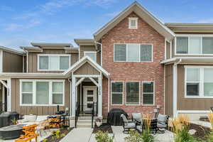 View of front facade featuring an outdoor living space with a fire pit, board and batten siding, brick siding, and a patio