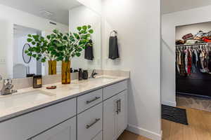 Bathroom with double vanity, a walk in closet, and light wood-type flooring