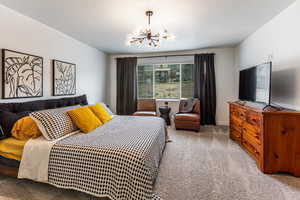 Carpeted bedroom with a chandelier and a textured ceiling