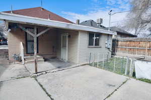 Back of property with a patio, roof with shingles, and a carport