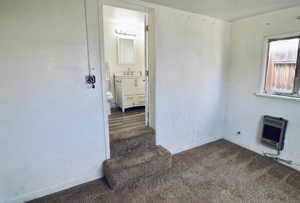 Unfurnished room featuring heating unit and carpet