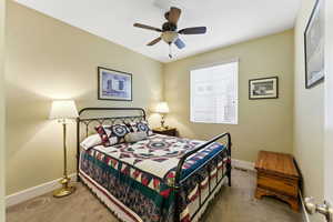 Bedroom with light carpet and a ceiling fan