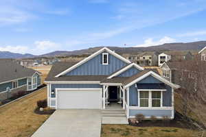 View of front of property featuring board and batten siding, roof with shingles, driveway, and a garage