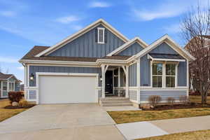 View of front of property featuring board and batten siding, roof with shingles, concrete driveway, and an attached garage