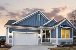 View of front of house with board and batten siding, a shingled roof, driveway, and an attached garage