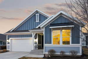 View of front of house featuring board and batten siding, driveway, a shingled roof, and an attached garage