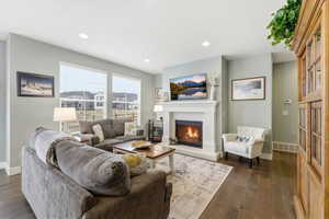 Living area featuring a warm lit fireplace, dark wood-type flooring, and recessed lighting