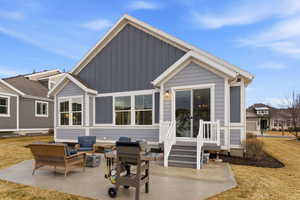 Rear view of property featuring board and batten siding, outdoor seating, a patio, a yard, and entry steps