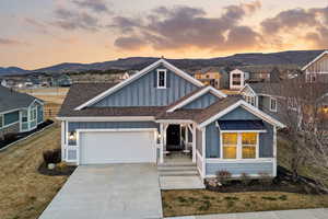 View of front facade featuring board and batten siding, roof with shingles, driveway, a mountain view, and an attached garage