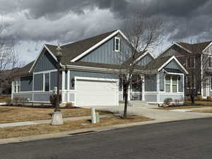 View of front of house featuring roof with shingles, driveway, board and batten siding, and a garage