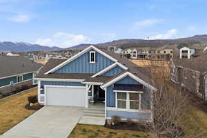 View of front facade with board and batten siding, a shingled roof, an attached garage, driveway, and a mountain view