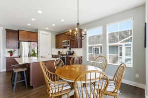 Dining area with hanging lights and dark wood-style floors
