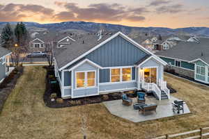 Back of property at dusk with a patio area, board and batten siding, a yard, and a mountain view