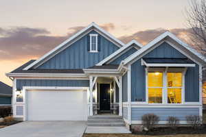 View of front of house with board and batten siding, roof with shingles, concrete driveway, and a garage