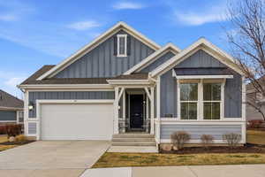 View of front of home featuring board and batten siding, roof with shingles, driveway, and a garage