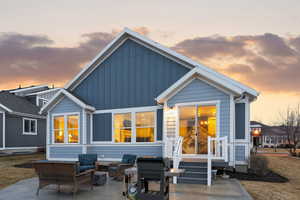 Back of house at dusk featuring outdoor lounge area, board and batten siding, and a patio area