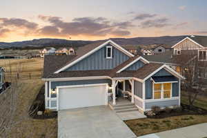 View of front of home with board and batten siding, roof with shingles, concrete driveway, a garage, and a porch