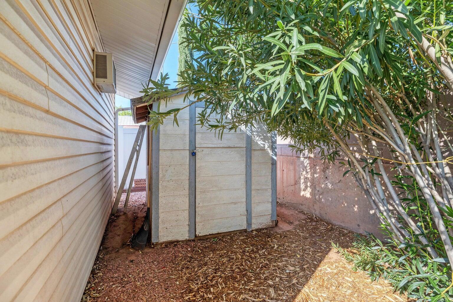 White siding exterior with a pitched roofline, accompanied by an outdoor storage shed