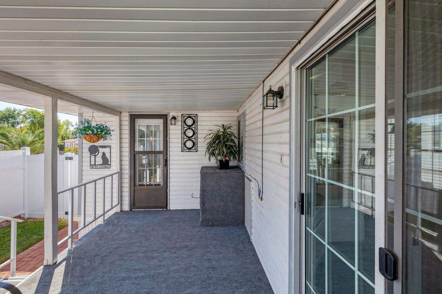Covered porch with outdoor carpeting and white vinyl siding