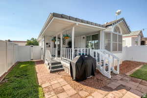 View of front of property with a fenced backyard, a gate, a wooden deck, and a sunroom