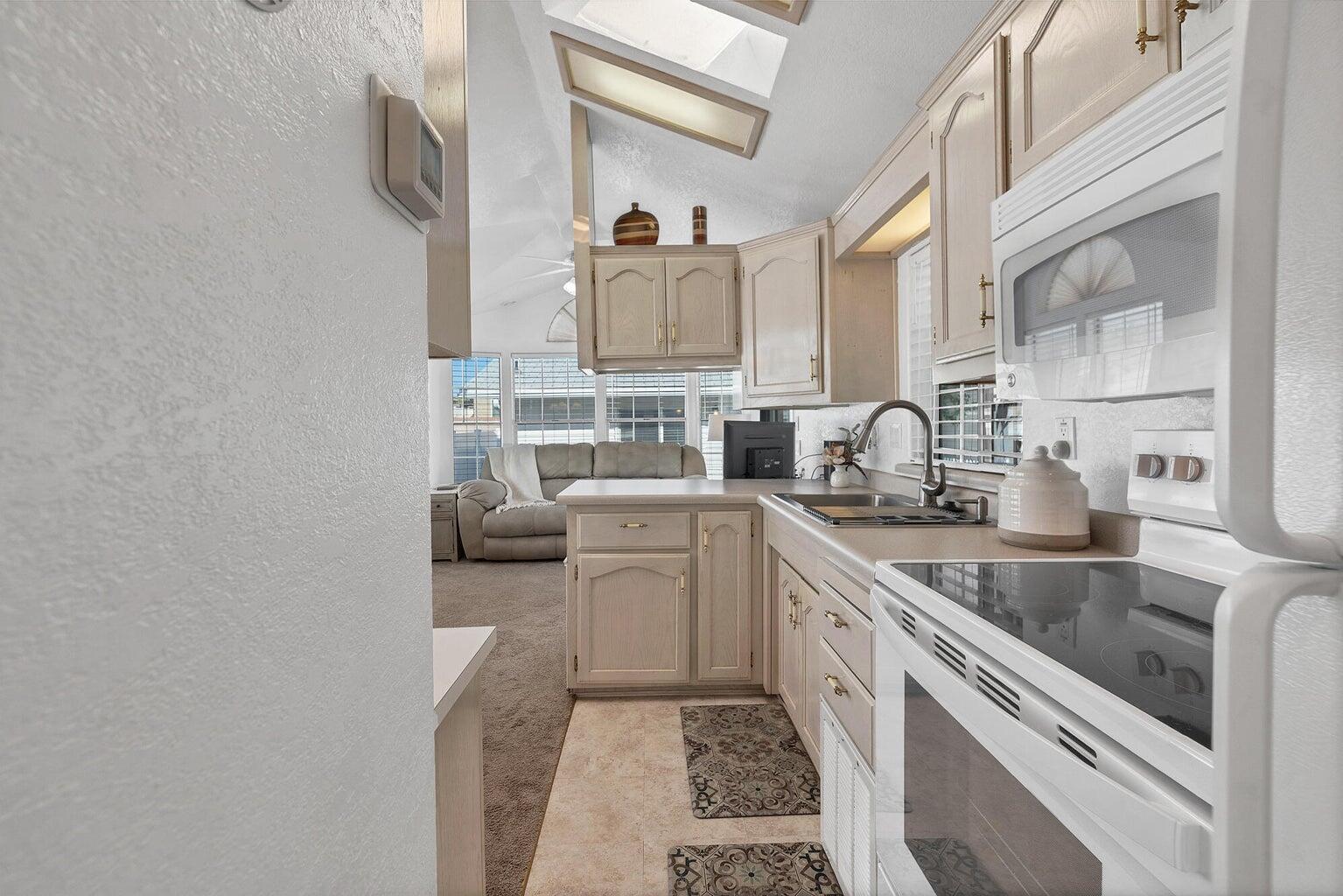 Galley kitchen featuring light cabinetry, integrated appliances, and a skylight for natural illumination
