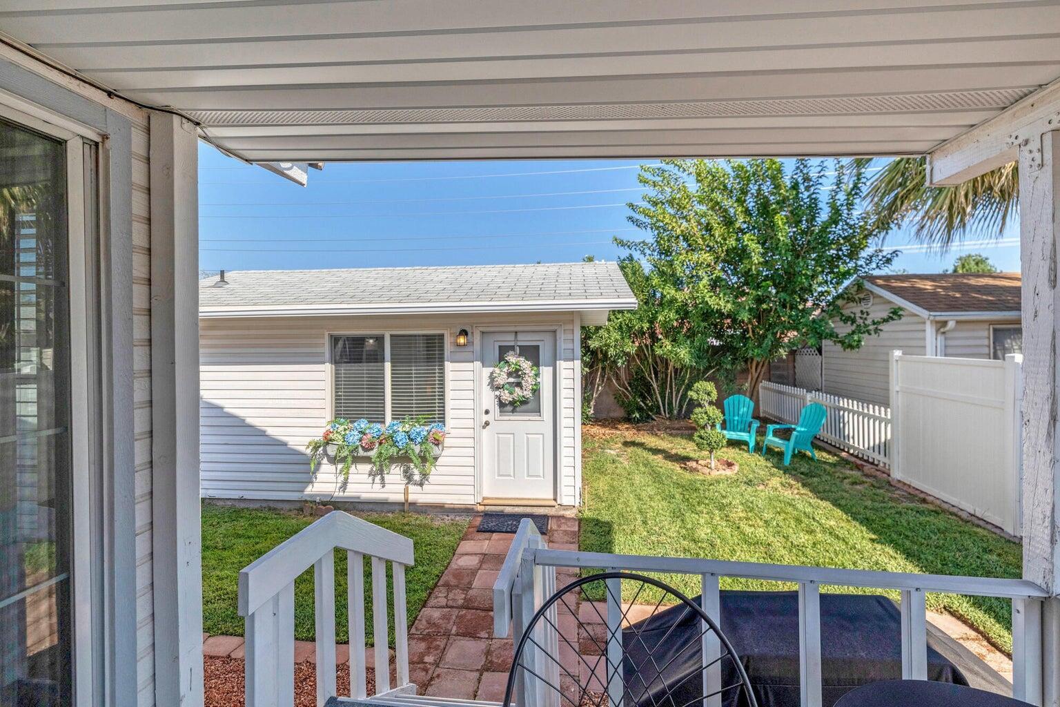 Covered patio area with white railing overlooking a fenced yard