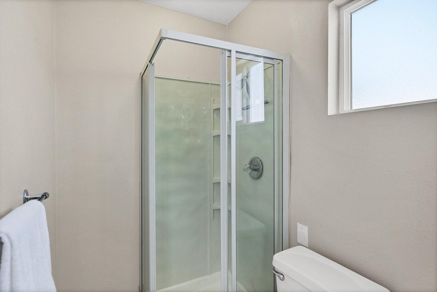 Corner shower enclosure with clear glass doors and a built-in shelf
