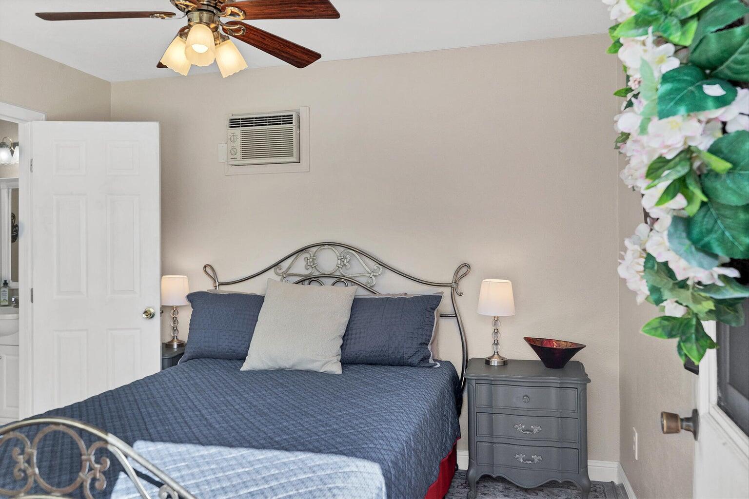 Room featuring a ceiling fan with integrated lighting, a wall-mounted air conditioning unit, and wood-finish flooring