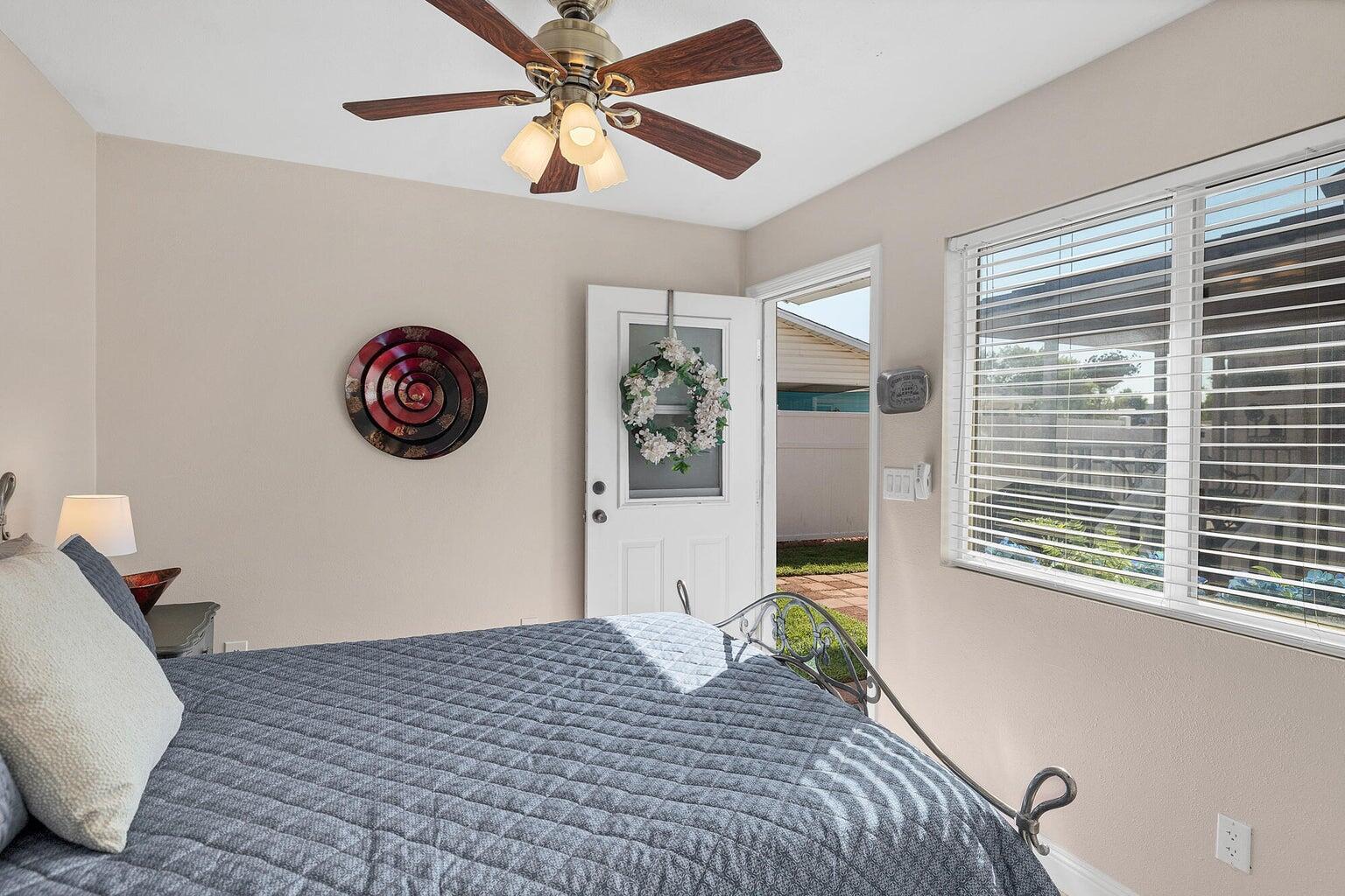 Interior room featuring a ceiling fan with integrated lighting, a multi-pane window with blinds, and direct access to an exterior area
