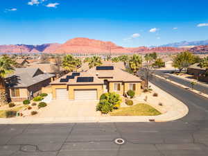 View of front facade with roof mounted solar panels, a garage, stucco siding, driveway, and a mountain view