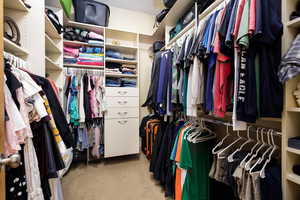 Walk in closet with light colored carpet