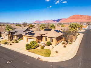 View of front of property featuring a mountain view, a garage, driveway, solar panels, and stucco siding
