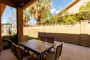Fenced backyard with a patio, a playground, and outdoor dining space