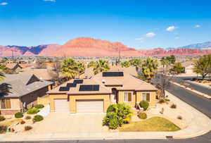 View of front of house featuring roof mounted solar panels, an attached garage, stucco siding, a mountain view, and driveway