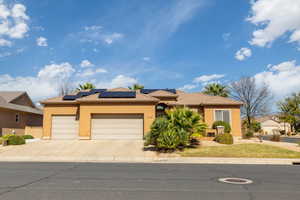 View of front facade with roof mounted solar panels, stucco siding, a garage, driveway, and a tiled roof