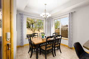 Dining room with suspended lighting, healthy amount of natural light, a tray ceiling, and light tile patterned floors