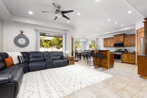 Living area with ceiling fan, a raised ceiling, and suspended lighting