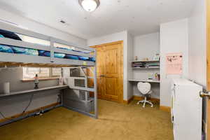 Bedroom with light carpet and built in study area
