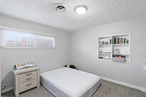 Bedroom with a textured ceiling and light carpet