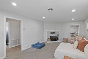 Bedroom with recessed lighting, light colored carpet, and a tiled fireplace