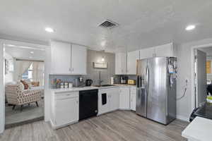 Kitchen featuring black appliances, white cabinetry, light wood-type flooring, tasteful backsplash, and recessed lighting