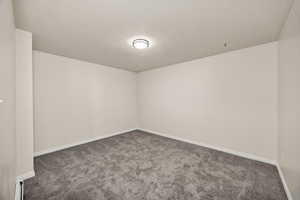 Unfurnished room featuring dark carpet and baseboards