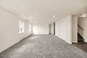 Unfurnished bedroom featuring a baseboard radiator, recessed lighting, carpet floors, and two closets