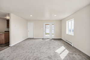 Unfurnished living room with a baseboard radiator, carpet, and recessed lighting