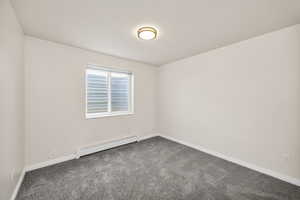 Unfurnished room featuring a baseboard radiator and dark colored carpet