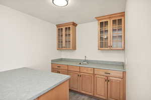 Kitchen with glass insert cabinets, light countertops, light wood-style floors, a textured ceiling, and wood finish cabinetry