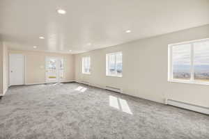 Empty room with a baseboard heating unit, recessed lighting, carpet flooring, and a baseboard radiator