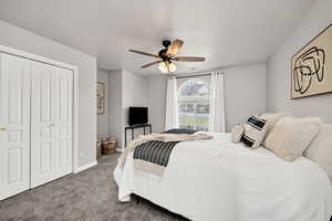 Bedroom with a ceiling fan, carpet, and a closet