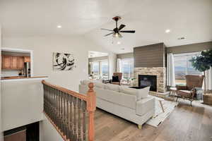 Living area featuring a stone fireplace, light wood-type flooring, ceiling fan, and recessed lighting
